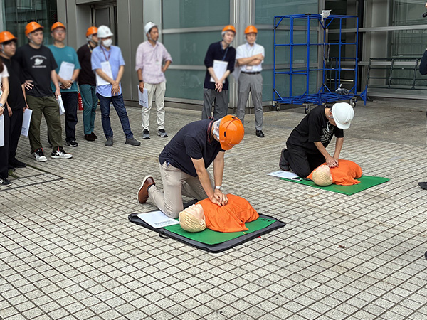 社内の避難訓練の様子。公益財団法人 東京防災救急協会の指導により、胸骨圧迫を練習する参加者たち