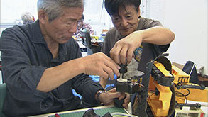 おもちゃをなおす野口三郎さん(左)と石原久芳さん(右)